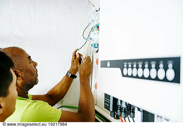Engineer with colleague installing system in utility room
