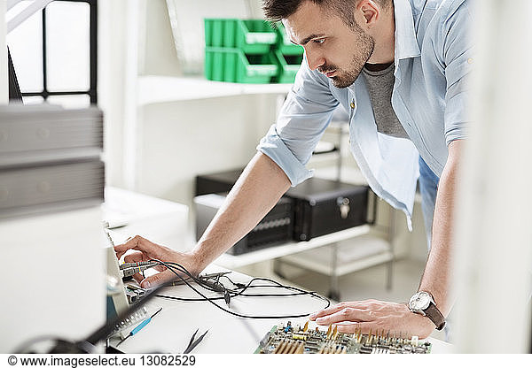 Engineer working with circuit boards at table in electronic laboratory