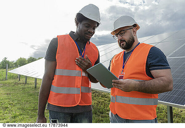 Engineers discussing with colleague over tablet PC at solar station