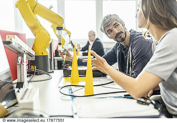 Engineers in factory developing new robot arm