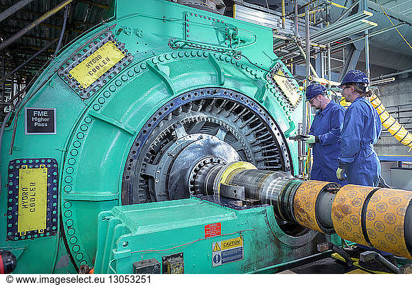 Engineers inspecting generator in nuclear power station during outage