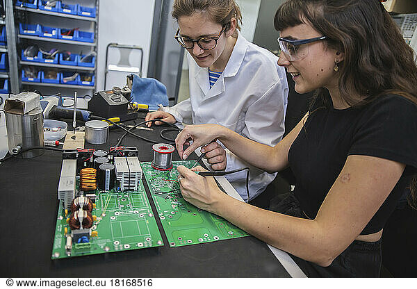 Engineers soldering circuit board together in electronics industry