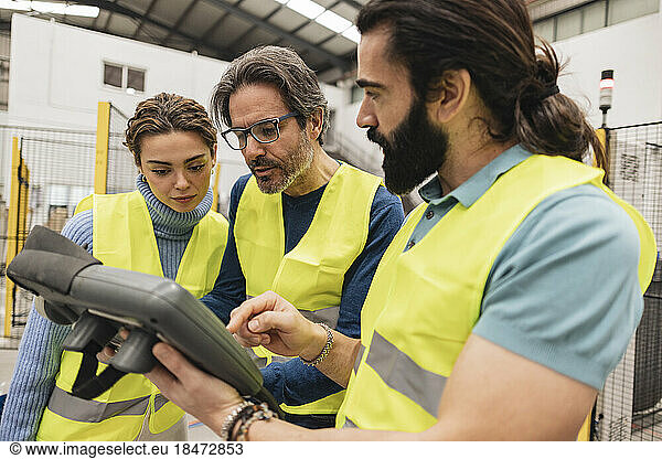 Engineers using controller in robotics factory