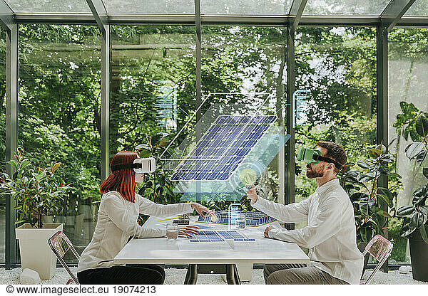 Engineers wearing virtual reality simulators designing solar panels