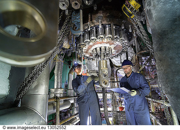 Engineers working in confined space under turbine during outage in nuclear power station
