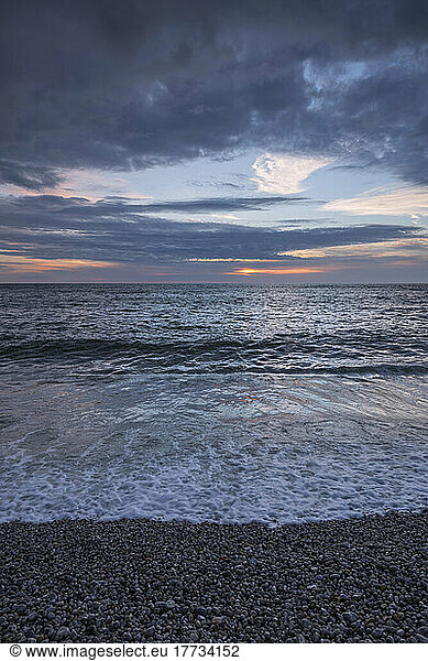 English Channel beach at dusk with clear line of horizon over sea in background