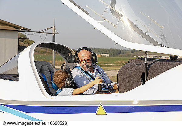 Enkel und Großvater sitzen in einem Flugzeug auf einem Flugplatz an einem sonnigen Tag