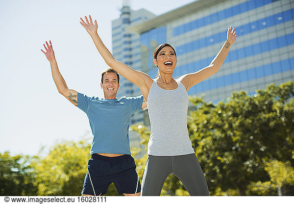 Enthusiastic couple exercising in urban park