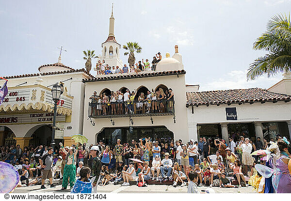 Enthusiastic crowds at a parade in Santa Barbara. The parade features extravagant floats and costumes.