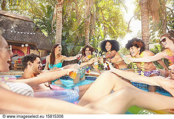Enthusiastic friends drinking  toasting beer bottles and cocktails at summer swimming pool party