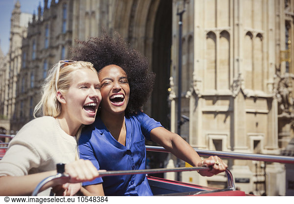 Enthusiastic friends laughing on double-decker bus in London