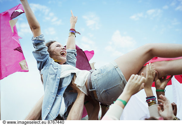 Enthusiastic woman crowd surfing at music festival