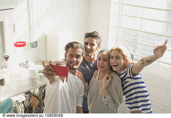 Enthusiastische junge erwachsene Mitbewohner nehmen Selfie in der Küche
