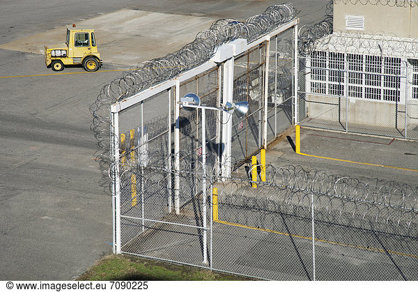 Entrance Gate and vehicle lock  a supervised entrance searching area  with high security fencing and barbed wire at a Correctional Facility.