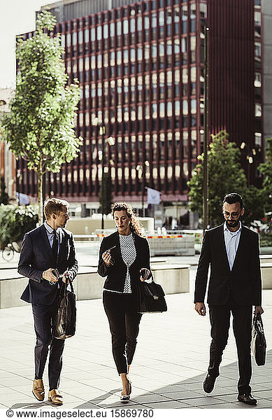 Entrepreneur discussing strategy with male and female colleagues while walking outdoors