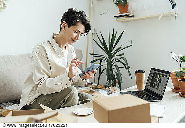 Entrepreneur using smart phone with boxes at store