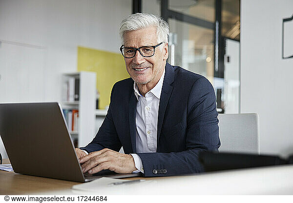 Entrepreneur with laptop smiling in office
