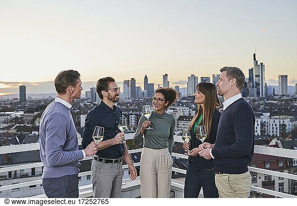 Entrepreneurs with drinks talking in city during sunset