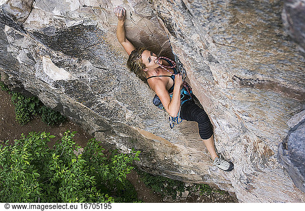 Entschlossene junge Frau klettert auf felsige Klippe
