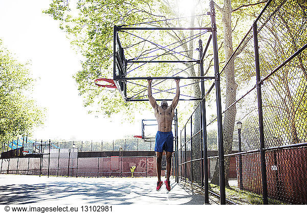 Entschlossener Athlet beim Klimmzug am Basketballkorb