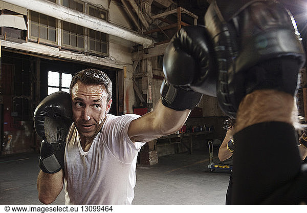 Entschlossener männlicher Boxer  der im Fitnessstudio trainiert