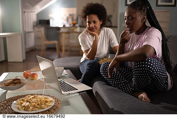 Entspannte multiethnische Freundinnen verbringen den Abend zusammen und schauen einen Film