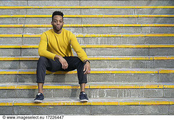 Entspannter Mann auf gelber Treppe sitzend