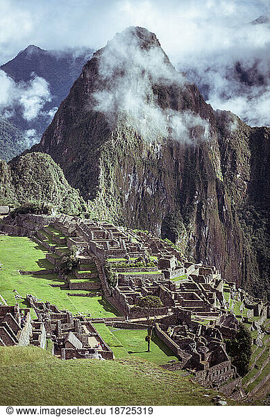 Epic view of mountains in clouds behind Machu Picchu inca city ruins
