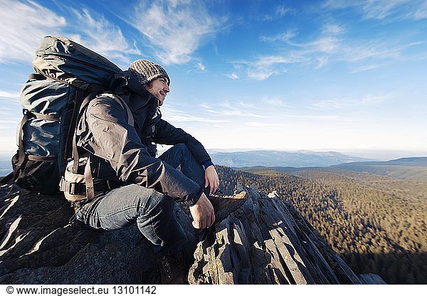 Erfolgreicher männlicher Wanderer sitzt auf Berg
