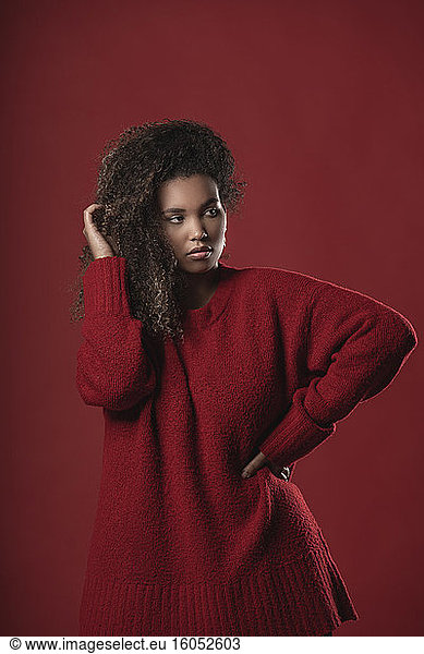 Ernste nachdenkliche Frau mit Pullover vor rotem Hintergrund