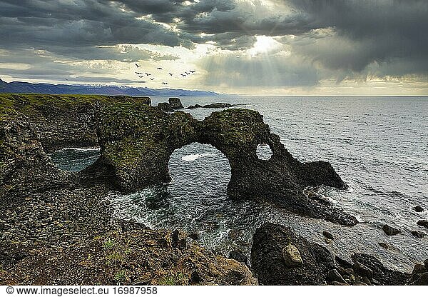 Eroded cliff at the Atlantic Ocean with Gatklettur and dramatic cloud formation  Arnarstapi  Faxaflói  Snæfellsnes Peninsula  Iceland  Europe