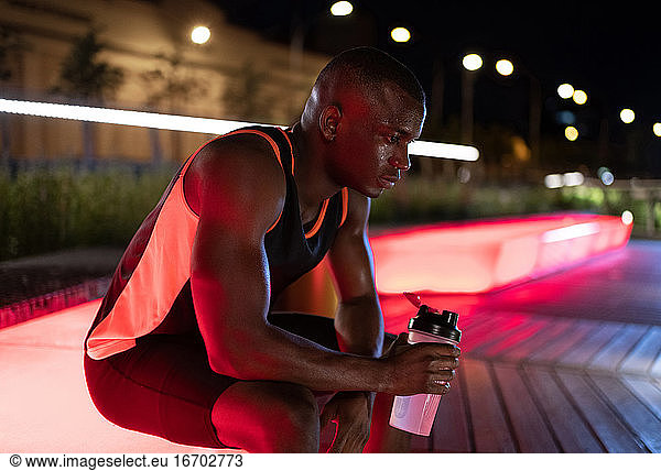 Erschöpfter afroamerikanischer Sportler trinkt Wasser