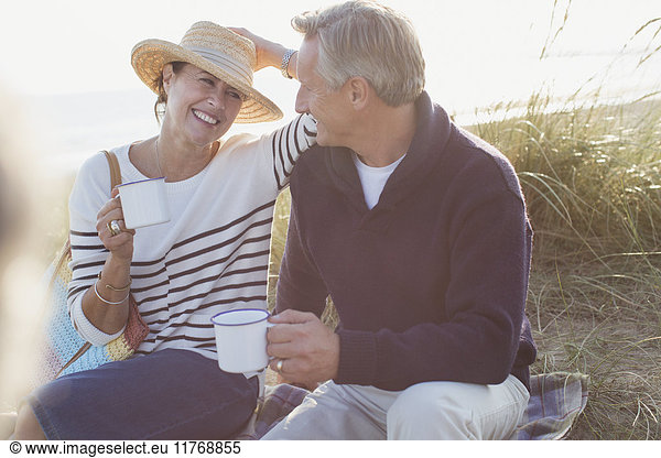 Erwachsenes Paar trinkt Kaffee im sonnigen Strandgras
