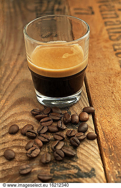 Espresso with coffee beans on wooden table  close up
