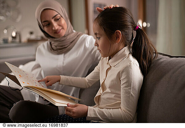 Ethnic daughter showing drawings to caring mother