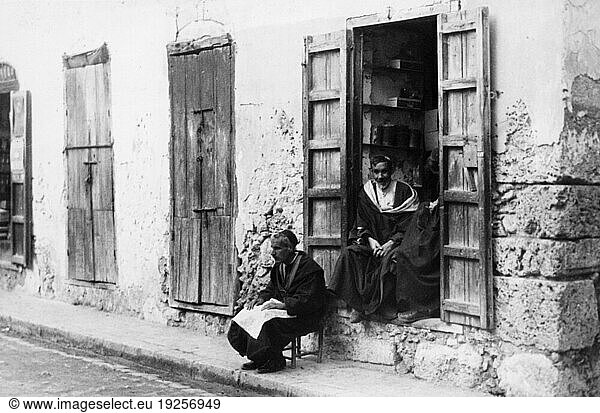 Ethnology:
Jewish People.
– Jewish craftsmen sitting on the steps of their workshop in the evening in Mazagan (El Jadida; since 2004 registeded as a World Heritage Site).
Photo  undated  1930's.