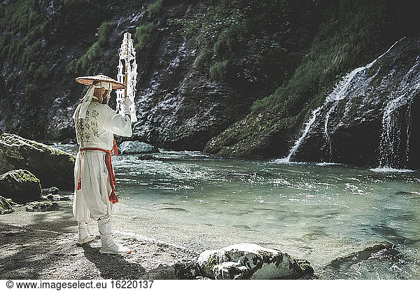 Europäischer Yamabushi-Mönch in traditioneller Shugendo-Robe macht Wasserzeremonie mit Gohei