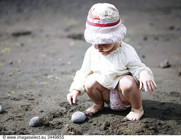 Europe  Spain  Canary Islands  Tenerife  Girl (2-3) playing with stone on beach
