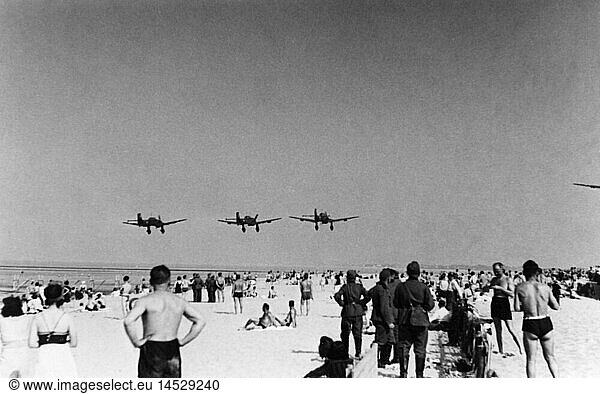 events  Second World War / WWII  aerial warfare  aircraft  a squadron of dive bombers Junkers Ju 87 B in low level flight over a beach  probably France  summer 1940  Ju87  Ju-87  Stukas  Stuka  German occupation  airplanes  aeroplanes  planes  Battle of Britain  1940s  40s  20th century  historic  historical  military  Third Reich  Wehrmacht  Germany  sunbathing  sunbath  sun bath  soldiers  people