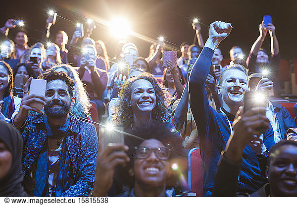 Excited audience with smart phone flashlights cheering