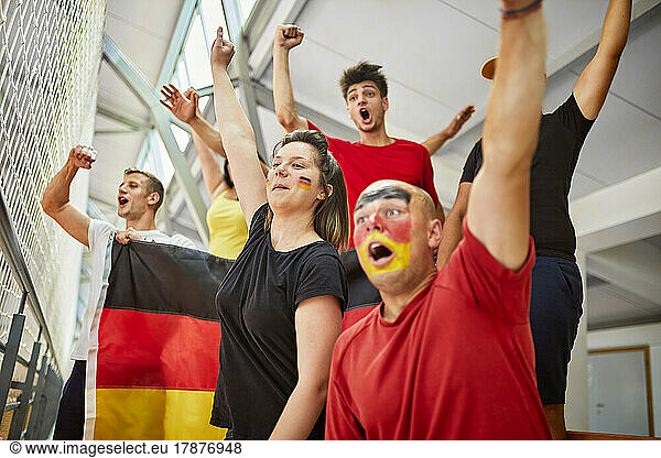 Excited fans cheering together watching sports event in stadium