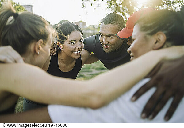 Excited female coach huddling with team at park