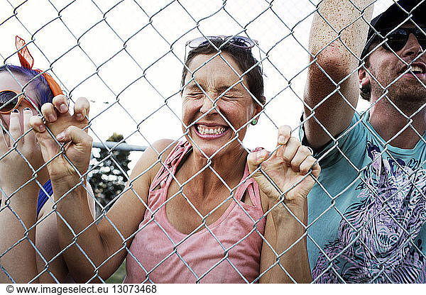 Excited female fan standing with spectators at chainlink fence