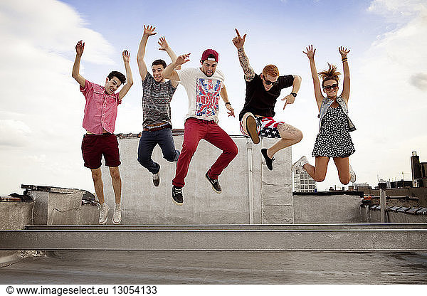 Excited friends jumping at building terrace