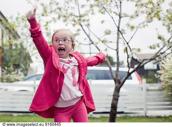 Excited girl with arms outstretched enjoying in lawn