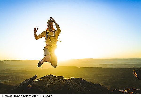 Excited hiker jumping on mountain at Canyonlands National Park