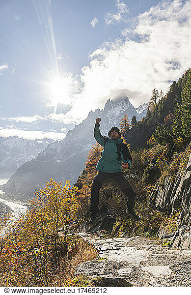 Excited man jumping in front of Aiguille des Grands Charmoz on sunny day  Chamonix  France