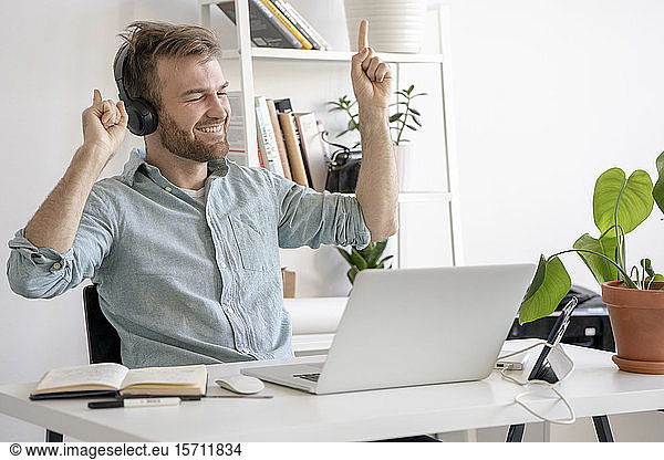 Excited man listening to music at desk in office