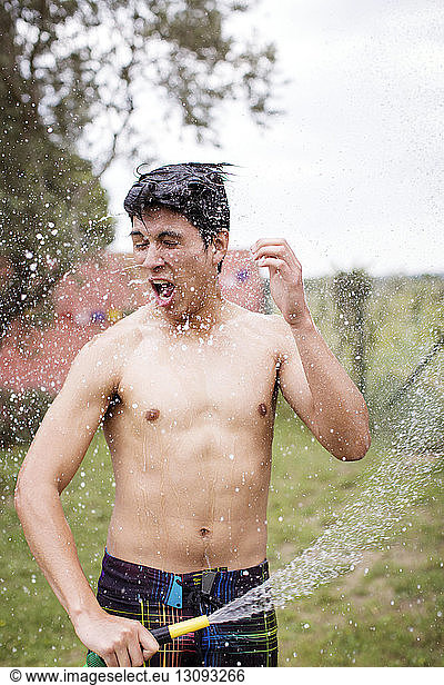 Excited man spraying water on self at yard