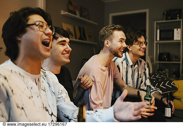 Excited multi-ethnic male friends watching sports at home